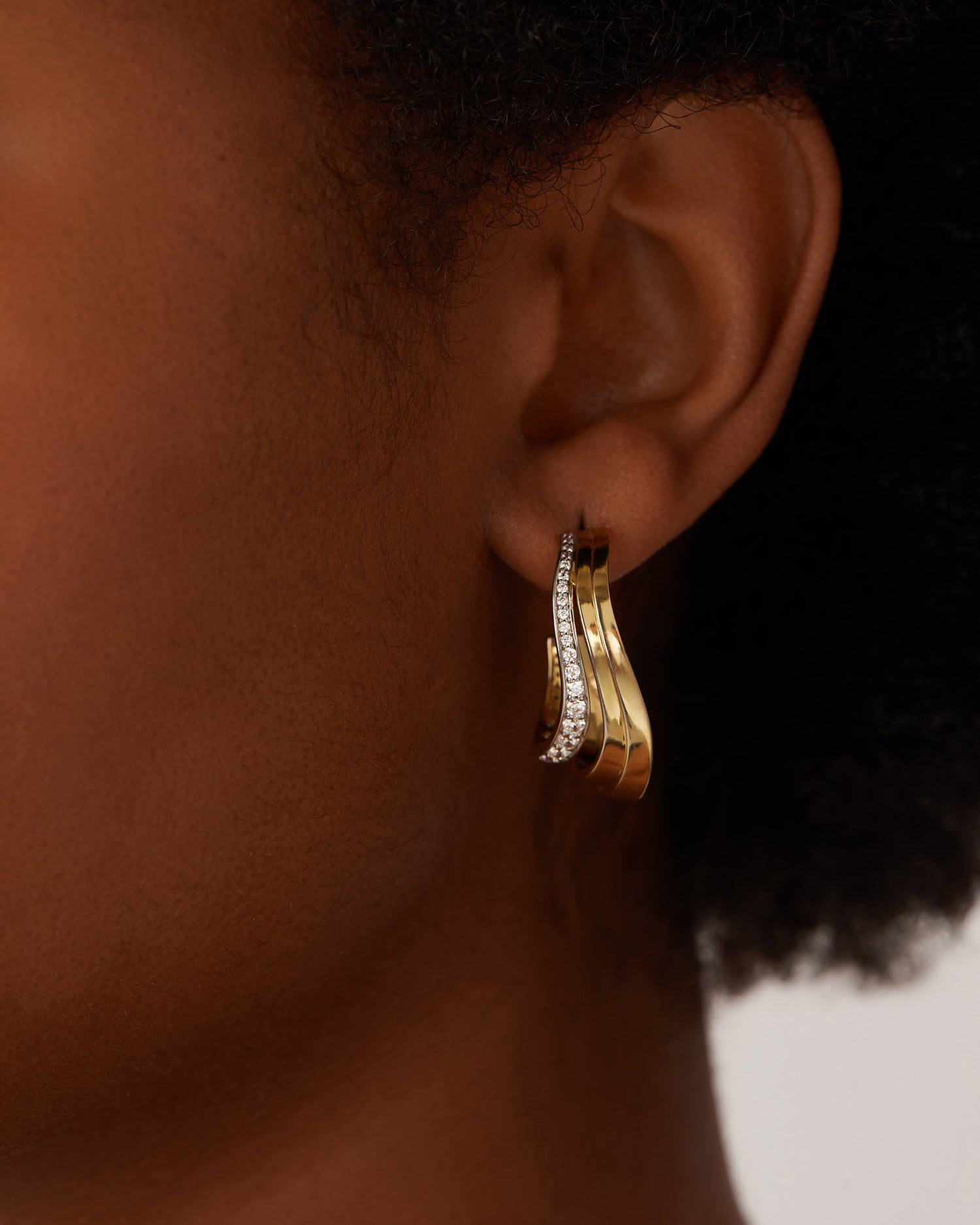 Close up of gold hoop earring with diamonds on earlobe